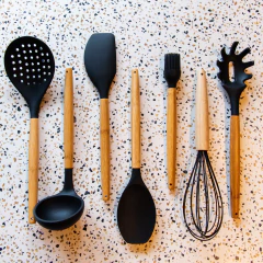 utensílios de silicone preto com o cabo de madeira em cima de uma bancada