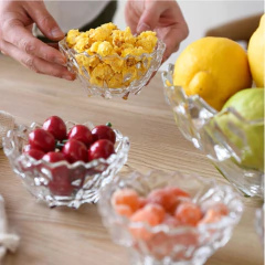 Taças de sobremesa de cristal com pipoca e frutas em uma mesa de madeira.