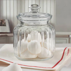 Pote de vidro hermético de 900ml com algodão dentro, em uma mesa com toalha branca e detalhes em vermelho.