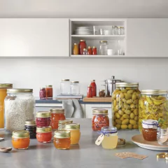 diversos potes de vidro com tampa de metal espalhados pelas bancadas e armários