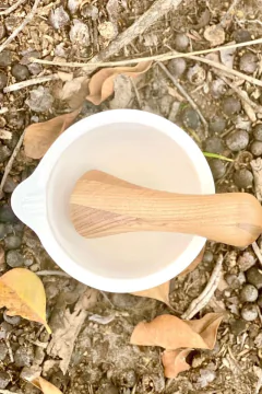um pilão de cerâmica branco com um socador de madeira de carvalho em uma superfície natural