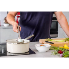 Homem usando uma concha de aço inox para retirar um ovo de uma panela em uma cozinha moderna.
