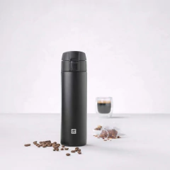 garrafa térmica preta redonda ao lado de grãos café