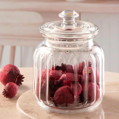 Pote de vidro hermético de 900ml com tampa, contendo decorações em vermelho sobre uma mesa de mármore.