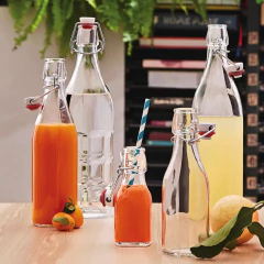 Conjunto de garrafas de vidro herméticas em uma mesa de madeira, contendo sucos de frutas coloridos e água.