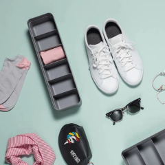 organizador colméia em fila chumbo com seis compartimentos com uma peça dobrada de roupa dentro ao lado de um par de sapatos