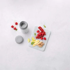 tábua com frutas cortadas ao lado de uma garrafa térmica branca / cinza