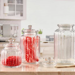 Potes de vidro hermético em uma bancada de cozinha, com doces coloridos dentro.