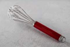 Batedor fouet vermelho da KitchenAid com alça para pendurar, ideal para misturar ingredientes na cozinha.