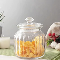 Pote de vidro hermético de 900ml com tampa, cheio de salgadinhos, sobre uma mesa decorada.