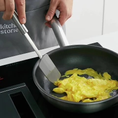 mulher usando uma espátula para mexer um ovo fritando 