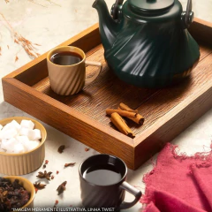 Caneca de cerâmica Twist Classic de 300ml da Ceraflame Gourmet, ao lado de uma chaleira verde e acompanhada de canela e açúcar em uma bandeja de madeira.