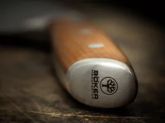 Um close up do detalhe no cabo de uma faca da marca Böker, importada da Alemanha em uma mesa