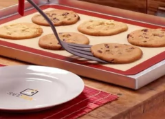 pessoa usando uma espátula para tirar biscoitos de cima do tapete de silicone dentro de uma forma