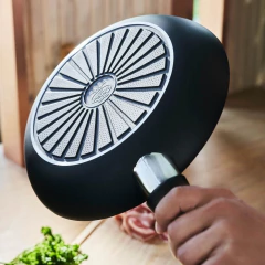 homem segurando a frigideira trinta e dois centímetros ballarini com exterior e cabo pretos com detalhes aço inox e fundo gravado com a marca