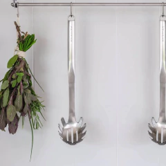 Pegador de massas premium em aço inox com alça, pendurado em um suporte na cozinha.
