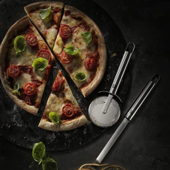 pizza fatiada ao lade de um cortador de pizza em aço inox gravado com a marca e com alça de pendurar