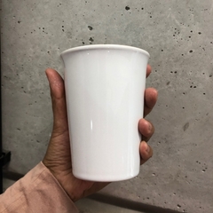 uma mão segurando um copo de cerâmica na cor branco