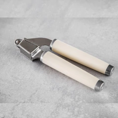 Espremedor de alho KitchenAid com cabos brancos e acabamento em metal.