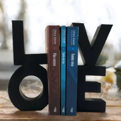 palavra love dividida em duas partes, a letra L em cima da letra O e a letra V sob a letra E, as letras estão de forma maiúscula e pintadas de preto, há livros no meios das duas partes colocados de forma reta.