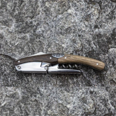 um saca-rolhas abridor de vinhos modelo primitivo de aço inox com acabamento de madeira nobre da marca italiana Legnoart, modelo de dois estágios com cortador de lacre em cima de uma superfície natural