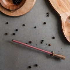 uma Chaira De Afiação De Facas de cerâmica com cabo de madeira de carvalho da marca alemã Nesmuk sobre uma mesa com temperos