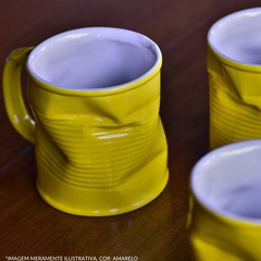 Caneca de cerâmica amarela com design amassado, mostrando o interior branco, em uma mesa de madeira.