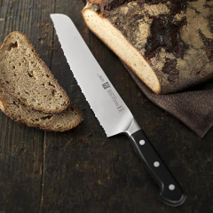 faca para pão com cabo sintético preto e lâmina gravada com a marca do lado de um pão