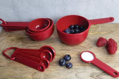 Conjunto de 4 xícaras medidoras vermelhas da KitchenAid, com frutas como mirtilos e framboesas ao lado.