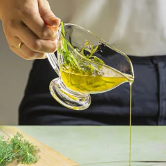 Molheira de vidro transparente com azeite e ervas sendo servida.