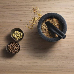 pilão de granito preto com grãos dentro e em cima de uma bancada