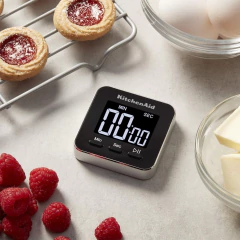 Temporizador digital magnético KitchenAid ao lado de ingredientes como framboesas, bolachas e ovos.