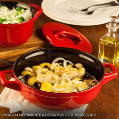 frigideira de cerâmica redonda vermelha com o interior preto servindo uma refeição