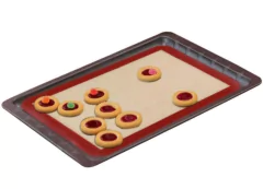 esteira de forno de silicone retangular branca com as bordas vermelhas dentro de uma forma com biscoitos em cima