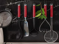Conjunto de utensílios de cozinha com cabos vermelhos, incluindo uma peneira, colher, espátula, concha e um escorredor, dispostos sobre uma superfície preta de mármore.
