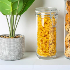 um pote de vidro hermético cheio de macarrão ao lado de uma planta