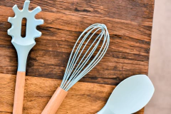 utensílios com a ponta de silicone azul com cabo de madeira em cima de uma bancada