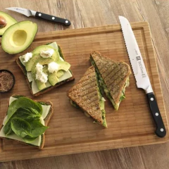faca para pão com cabo sintético preto e lâmina gravada com a marca do lado de um sanduíche