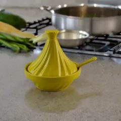 Mini tagine saleiro de cerâmica na cor amarela, com tampa, sobre uma bancada de cozinha.