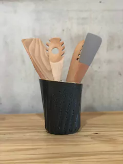 Porta utensílios de cerâmica na cor azul orgânico, contendo colheres de madeira e espátula de silicone.