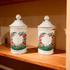 Par de potes de farmácia vintage de porcelana branca com tampa, decorados com pintura floral colorida