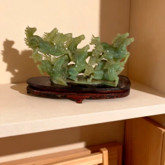 Escultura vintage chinesa de jade representando sete cavalos em movimento sobre base de madeira escura