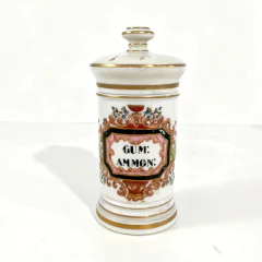 Pote de farmácia vintage de porcelana branca com detalhes dourados e decoração floral, rotulado "GUM: AMMON:"