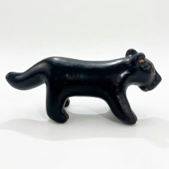 Escultura indígena de cerâmica representando um animal negro com detalhes em laranja, estilo Waujá