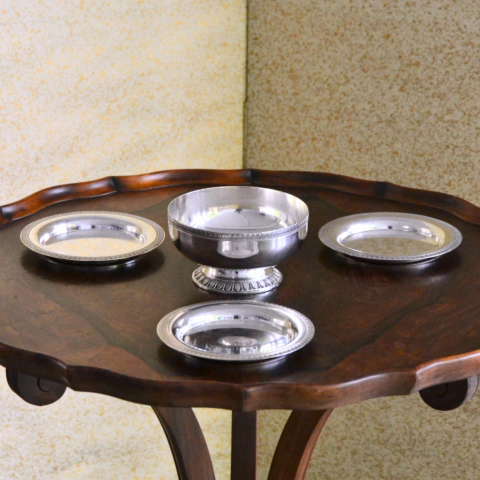 Conjunto vintage de quatro peças Christofle em prata, incluindo três coupelles e uma compoteira, exibidos sobre mesa de madeira escura