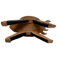 Banco indígena do povo Mehinaku esculpido em madeira com pintura tradicional em preto, formato que representa uma aranha