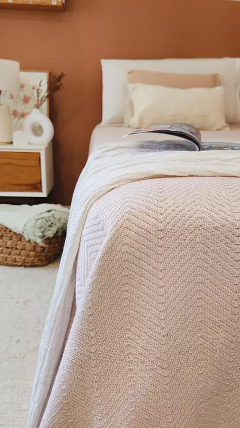 Cubrecama rosé tejido con diseño en espiga sobre cama individual en cuarto de estilo moderno y cálido