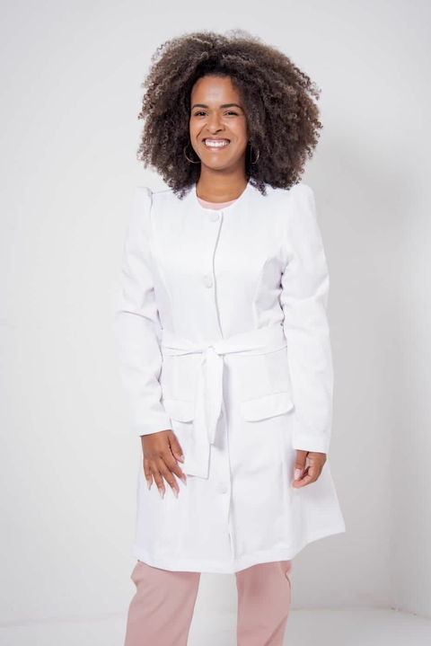 Mulher sorrindo vestindo jaleco feminino branco com cinto na cintura e bolsos frontais
