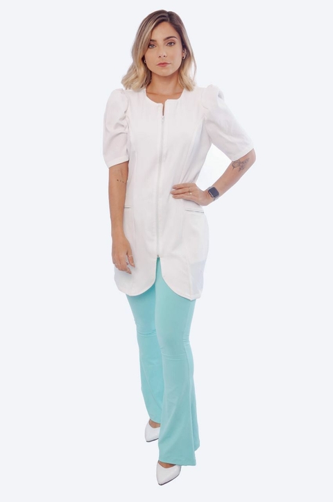 Mulher vestindo jaleco feminino branco Deborah com mangas bufantes e zíper frontal, combinado com calça azul clara e sapatos brancos