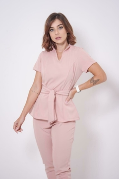 Mulher usando scrub rosa claro Cíntia Flex com calça e blusa de mangas curtas com cinto na cintura